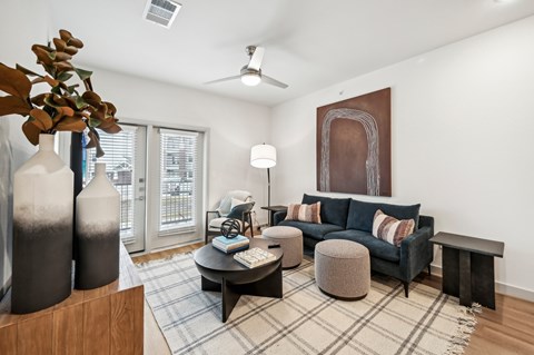 A living room with a blue couch and a large painting on the wall.